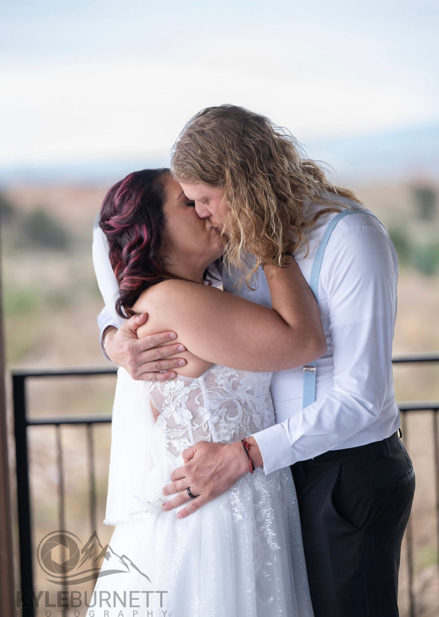 Bride and groom embrace by the deck railing at Observer Ranch, Penrose Colorado